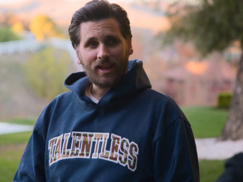 Scott Disick wears a dark blue, almost teal hoodie.