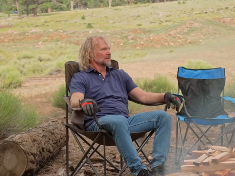 Kody Brown sits by an outdoor fire.
