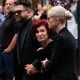 Jack Osbourne, Sharon Osbourne and Kelly Osbourne leave after viewing tributes to the late Ozzy Osbourne from fans as his funeral cortege travels through his home city of Birmingham on July 30, 2025 in Birmingham, England.