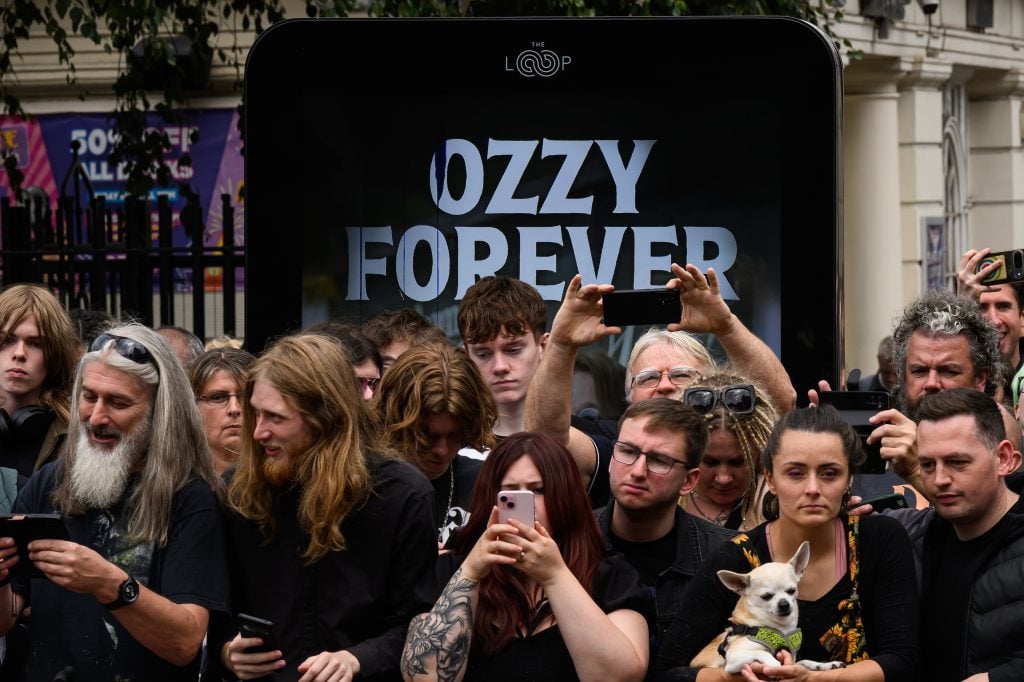 Ventilatori pulcējas pie Melnā sabata tilta pēc Osburnas ģimenes locekļu apmeklējuma, lai apskatītu veltījumus vēlajam Ozzy Osbourne, jo viņa bēru kortē 2025. gada 30. jūlijā Birmingemā, Anglijā, Birmingemā, Anglijā, ceļoja pa savu dzimto pilsētu Birmingemu.