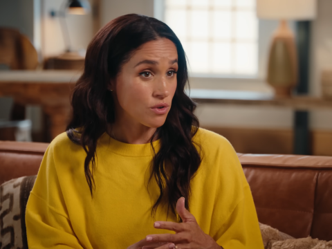 Meghan Markle in a yellow blouse while chatting.