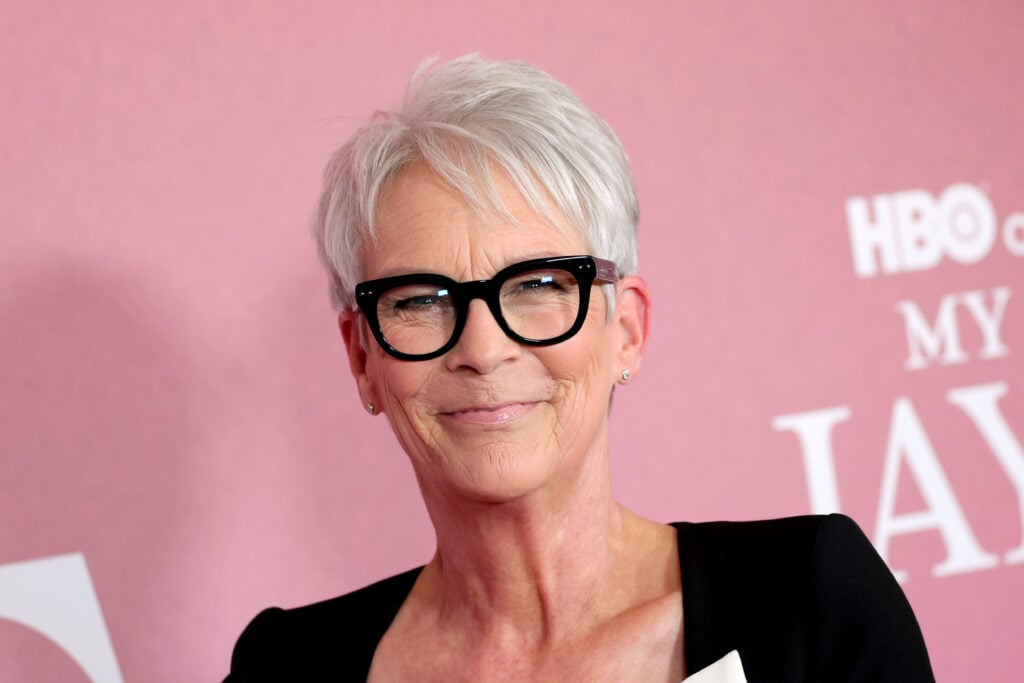 Jamie Lee Curtis com um fundo de ouro rosa.