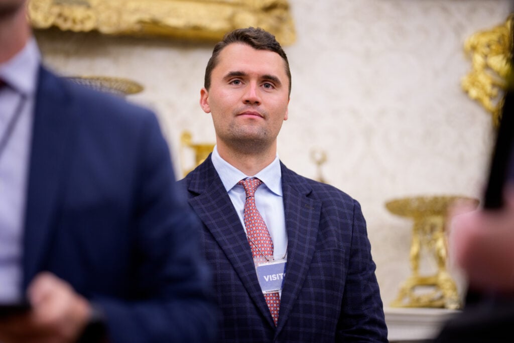 Turning Point USA co-founder Charlie Kirk stands in the back of the room as U.S. President Donald Trump speaks during a swearing in ceremony for interim U.S. Attorney for Washington, D.C. Jeanine Pirro in the Oval Office of the White House on May 28, 2025 in Washington, DC. 