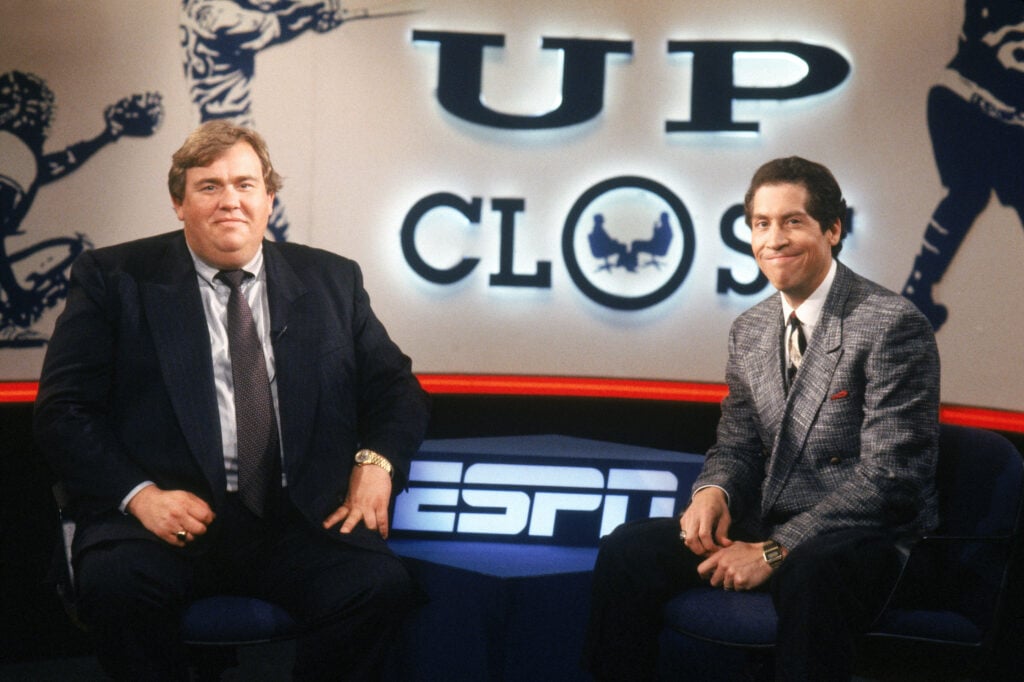 Sportscaster Roy Firestone sits with the late comedic actor John Candy (1950-1994) on the set of ESPN's "Up Close" in May of 1991.