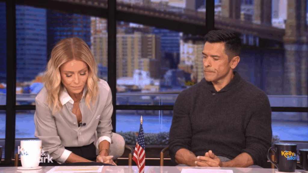 Kelly Ripa reads next to Mark Consuelos.
