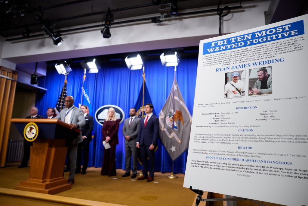 An FBI Ten Most Wanted poster is displayed during a news conference announcing the indictment of a former Olympic snowboarder Ryan Wedding, charging him with murder and money laundering in connection to a drug trafficking organization at the Justice Department on November 19, 2025 in Washington, DC.