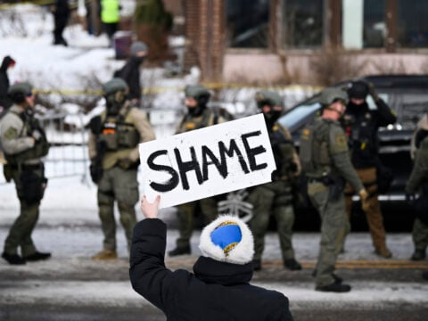 An onlooker holds a sign that reads
