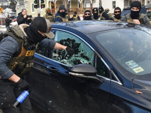 A federal officer breaks a car window as they begin the process of removing a woman from her vehicle near an area where ICE was operating in Minneapolis, Minnesota, on January 13, 2026.