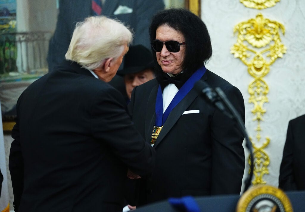 El presidente estadounidense Donald Trump (izq.) entrega la medalla de los Honores del Centro Kennedy 2025 al músico Gene Simmons (dcha.) de la banda de rock KISS durante una presentación de medallas en la Oficina Oval de la Casa Blanca el 6 de diciembre de 2025 en Washington DC. 