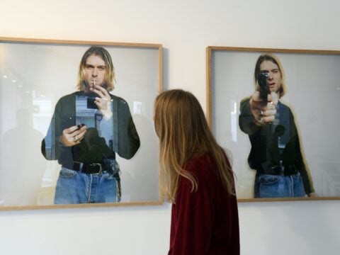 A woman looks at photos of late singer Kurt Cobain, posing with a handgun, as part of the exhibition 