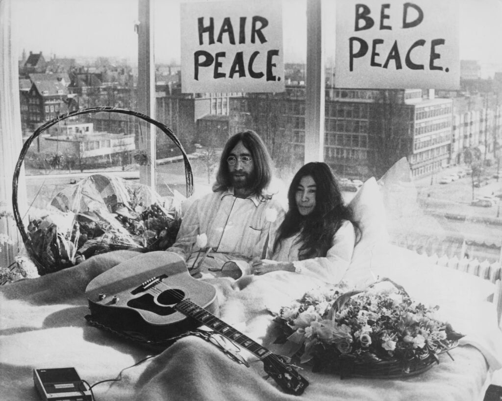 A week after their marriage, musicians John Lennon and Yoko Ono lay in their bed in the Presidential Suite of the Hilton Hotel, Amsterdam, 25th March 1969. 
