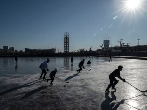 People play hockey on the frozen ice near the National Stadium at Olympic Park on January 13, 2022 in Beijing, China.