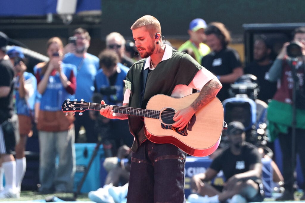 Justin Bieber holds his guitar on stage for the 2026 World Cup, a soccer event.