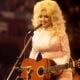 American singer, songwriter and actress Dolly Parton, performs with a guitar, 1976.