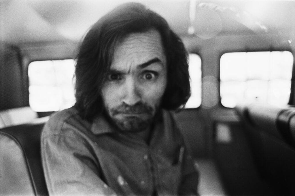 American criminal and cult leader Charles Manson (1934 - 2017) traveling on a police van to the Santa Monica Courthouse to appear in court for a hearing regarding the murder of music teacher Gary Hinman, Los Angeles, California, 25th June 1970.